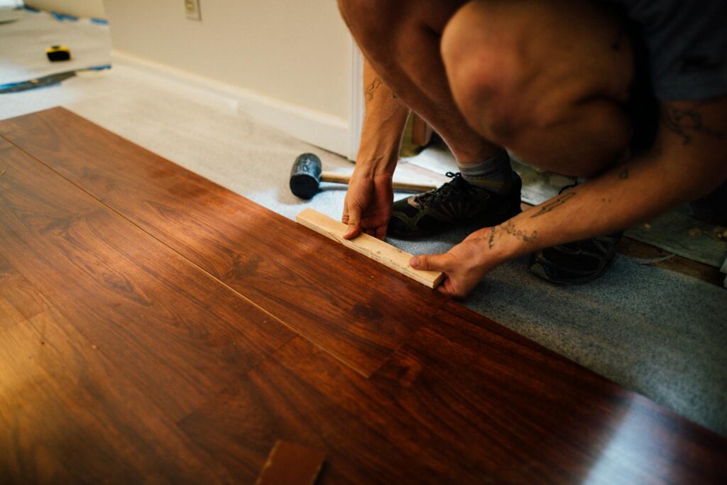Expert lays wooden floor indoors, showcasing precise craftsmanship and modern interior renovation.